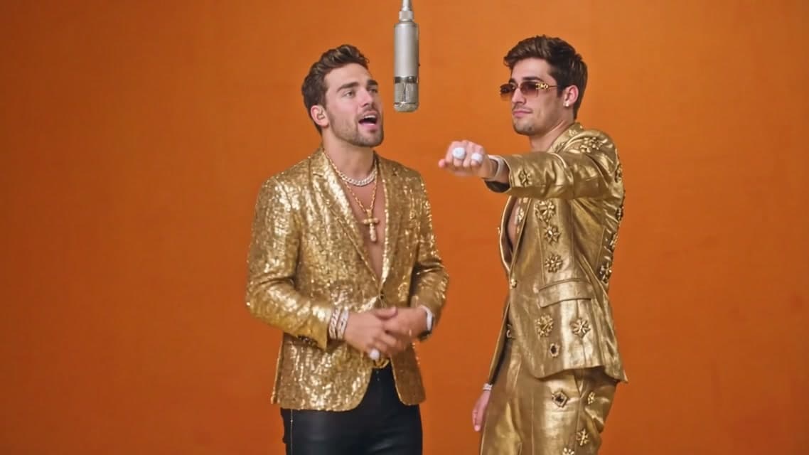 Hotel Lobby AI video showing two men in gold suits performing in an orange studio booth