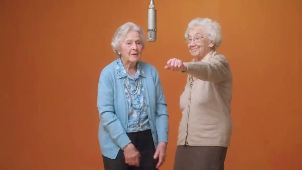Hotel Lobby AI video showing two elderly women in an orange studio booth with a hanging microphone